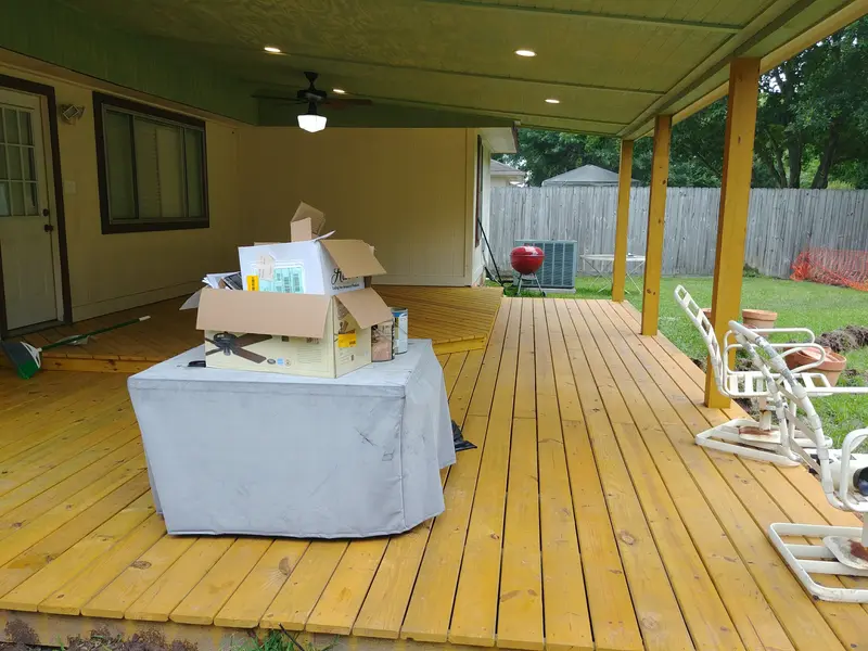 New covered deck with a boxed ceiling fan still sitting on a cloth-covered table